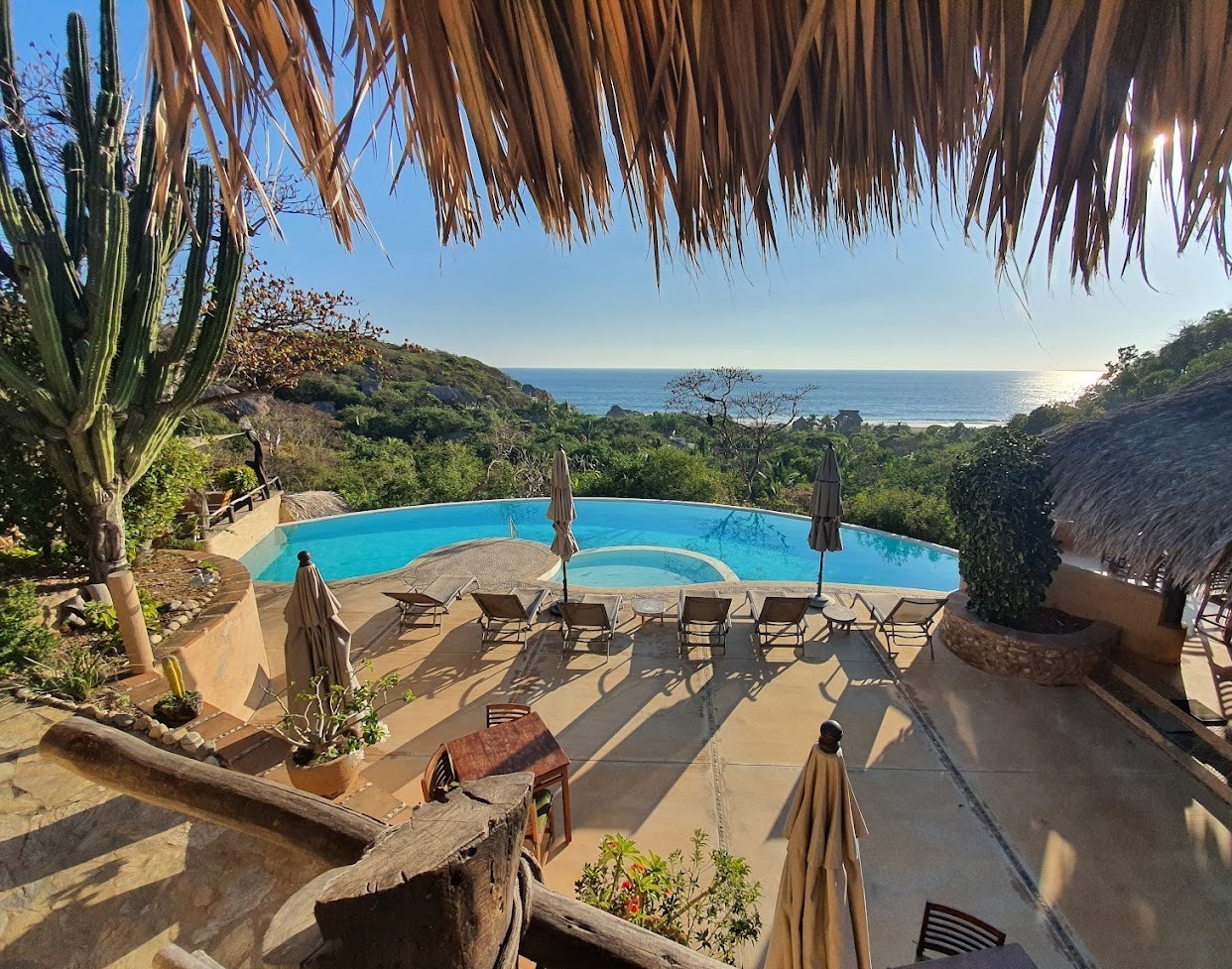 vista de hotel OceanoMar en Mazunte Oaxaca con piscina, áreas verdes y camastros